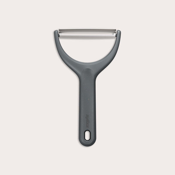 The Zyliss Wide Peeler features a Y-shaped design, ergonomic handle, and horizontal stainless steel blade, shown against a simple light background.